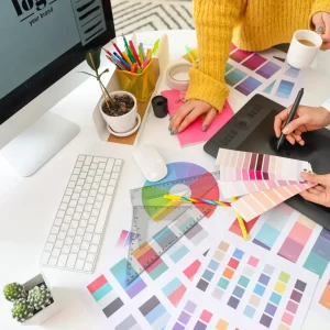 Branding color swatches laid out on a desk with the hands of two different people choosing between them.